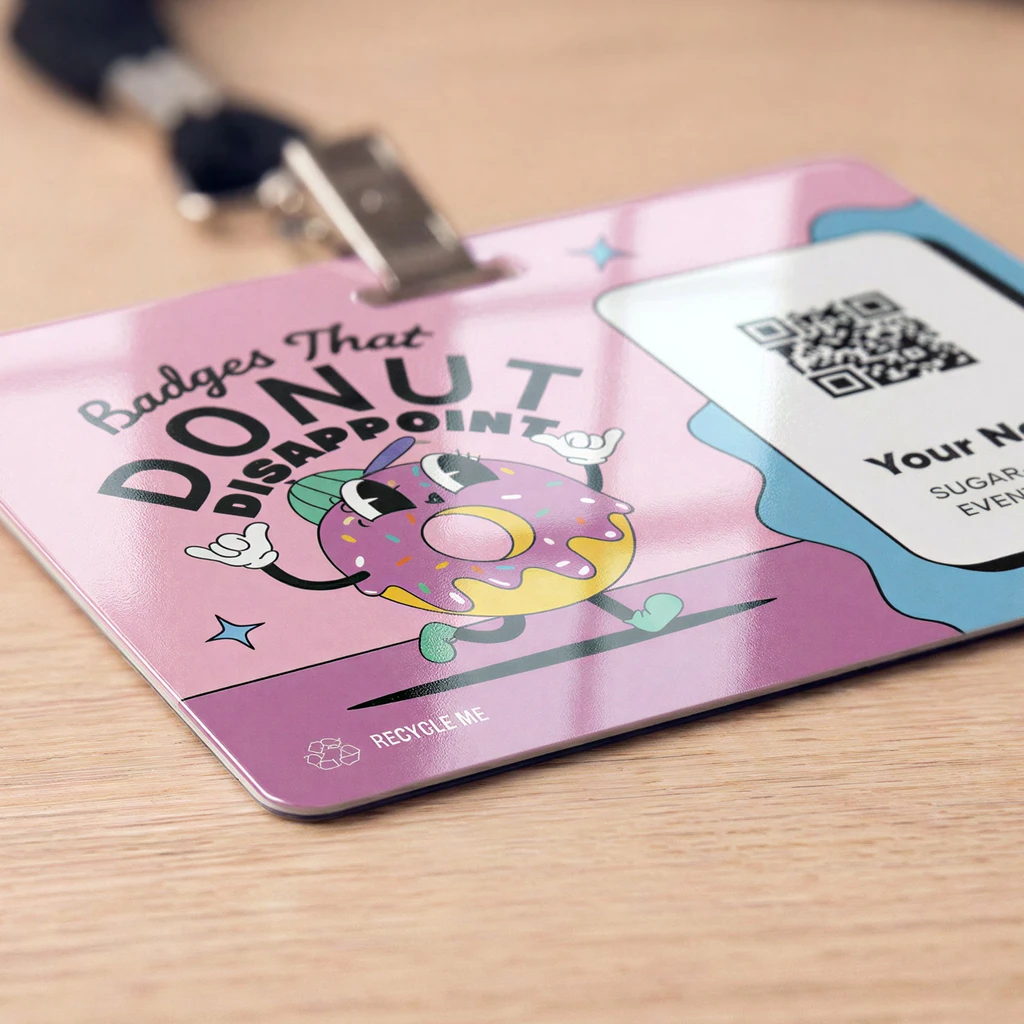 4 by 3 inch plastic event badge with a pink donut-themed design and QR code area, clipped to a lanyard